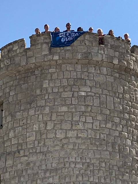 Students holding a GVSU flag over a tower edge